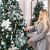 Woman decorating Christmas tree with light blue and white ornaments