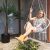 Woman relaxing in Springos grey macrame hanging chair on patio with plants