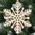 Springos Holzschneeflocke-Weihnachtsbaumschmuck, der an einem Weihnachtsbaum hängt