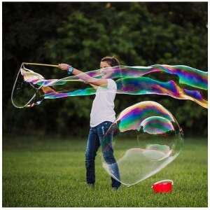 Child blowing giant bubbles with a bubble wand and solution - Bubble Blower