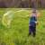 Child blowing giant soap bubble with FruBlu hoop bubble wand