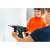 Child using Bosch cordless hammer drill toy for kids, green and red, to drill a hole in a wall