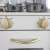 Close-up of the stovetop knobs of the white wooden play kitchen, featuring gold knobs