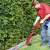 Man using the Einhell GC-ET 2522 electric grass trimmer to trim the edges of a lawn