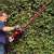 Man using Einhell GE-EH 7067 electric hedge trimmer to trim a hedge