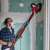 Man using Einhell TE-DW 225 X drywall sander with dust extraction to sand a wall
