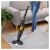 Woman using Sencor SVC 0741YL cordless stick vacuum cleaner on carpet