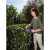 Woman using Gardena EasyCut Li-40 Cordless Hedge Trimmer, 14.4V, black and orange, to trim a bush