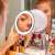 Woman using Navaris LED lighted magnifying makeup mirror with 7x magnification