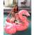 Intex Giant Flamingo Ride-On Pool Float, pink inflatable flamingo with handles, two children and one adult sitting on the float in the pool