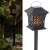 Solar powered flame light, black lantern with decorative cutouts, 12 LED lights, for outdoor use, ground stake mounting, in garden setting