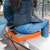 Woman sitting on THAW heated seat cushion, gray and orange