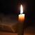 Brennende Spitzkerze im Dunkeln