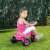 Toddler riding a pink unicorn trike in a grassy area