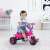 Toddler riding a pink unicorn trike in a room