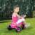 Toddler riding a pink unicorn trike in a grassy area