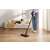 Woman using Dreame R10 Pro cordless stick vacuum cleaner, black, in living room