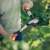 Person using Fiskars PowerGearX metal gear lopper with hook blade to cut a branch