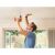 Man using Black and Decker cordless drill to install ceiling fixture