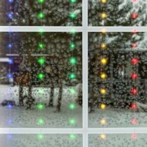 Micro LED curtain lights hanging on a window, showing the lights in different colors - Christmas