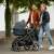 Couple walking with Maxi-Cosi Zelia3 stroller with bassinet, black frame and blue fabric