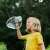 Child blowing a giant soap bubble with a wand