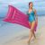 Woman carrying a pink Bestway inflatable beach mattress on the beach
