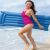 Woman carrying a blue Bestway inflatable beach mattress on the beach, smiling