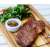 Grillezett steak fa vágódeszkán salátával és szószal
