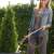 Woman using Gardena Comfort watering wand for hanging baskets to water a bush