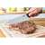 Tefal Essential chef's knife being used to cut a steak