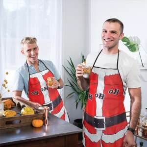 Two men wearing Santa Claus aprons, holding drinks in a kitchen setting - Apron