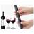 Black pneumatic wine opener in hand, with a bottle of wine and two glasses of wine in the background