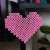Pink heart made with fuse beads, hanging on a wall