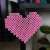 Pink heart made with fuse beads, hanging on a wall