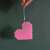 Pink heart made with fuse beads, hanging on a green string