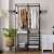 Black metal garment rack with shelves and hanging rods, in a bedroom setting