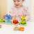 Child playing with a wooden shape sorting stacking toy, featuring a caterpillar design with different colored shapes to stack on each section