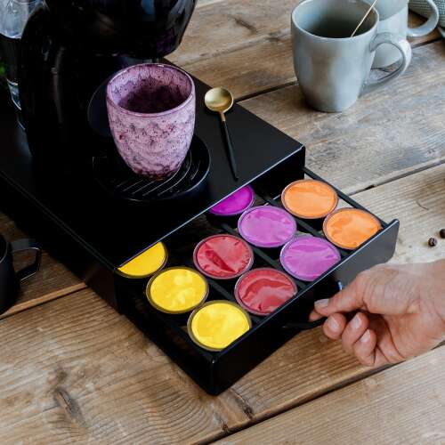 Čierny kovový držiak na kávové kapsuly Bewello s kapsulami Dolce Gusto a kávovarom navrchu
